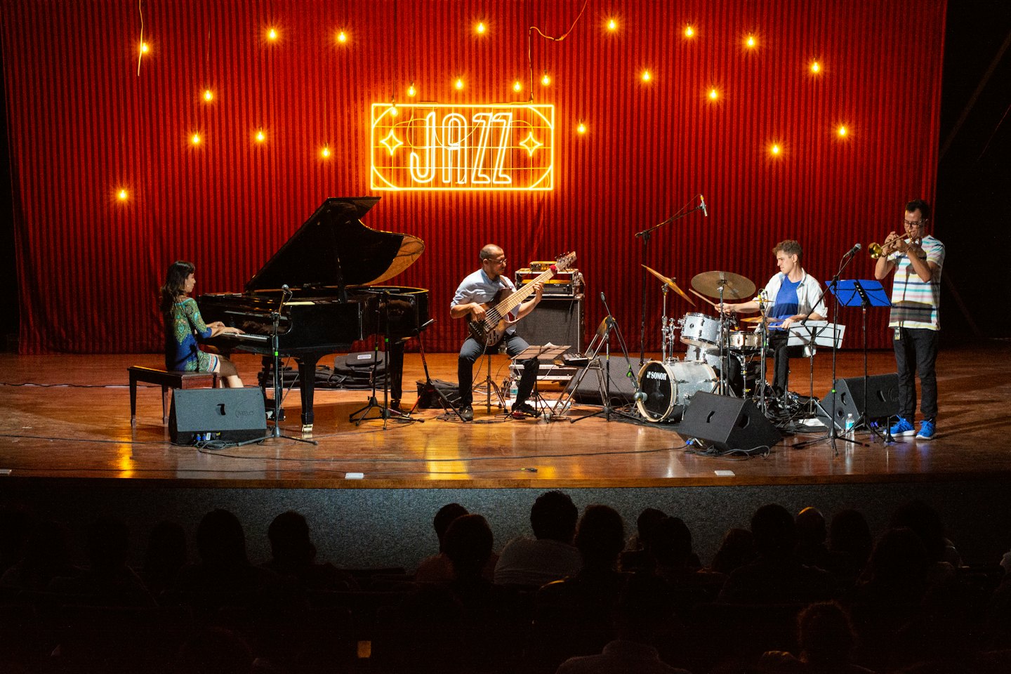 Gruppo jazz che suona sul palco con insegna al neon.